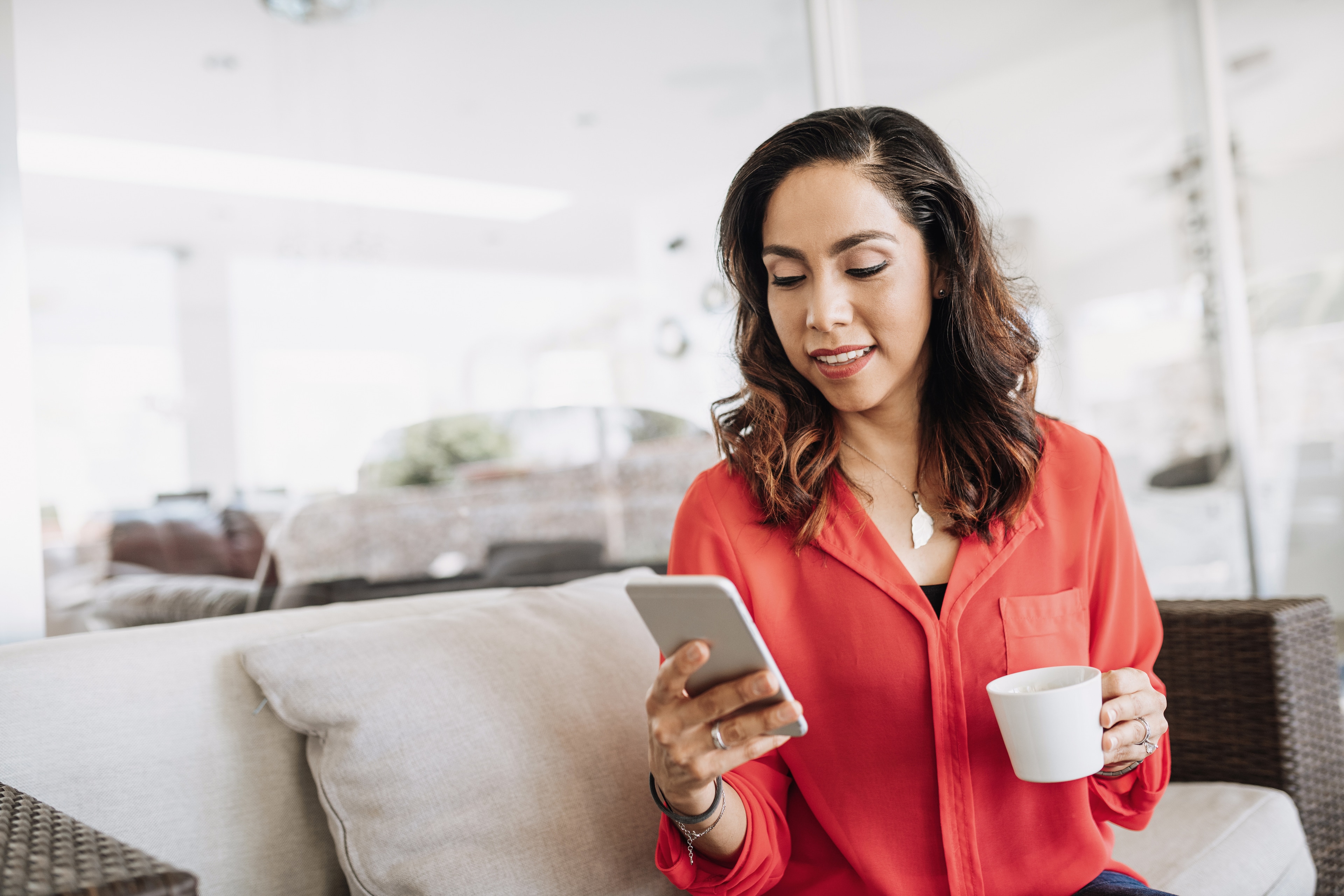 A woman holding a cup and a phone