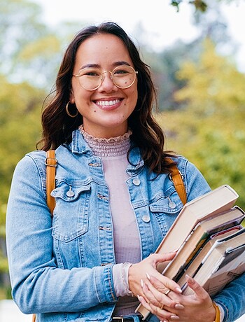 Smiling college student holding books on campus