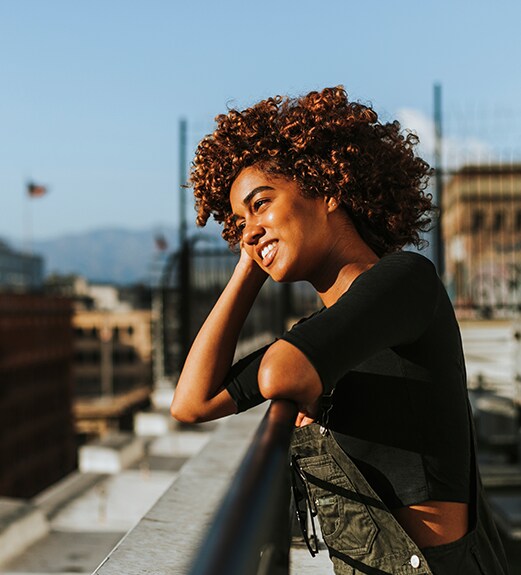 Young woman looking out at the city from the top of a building