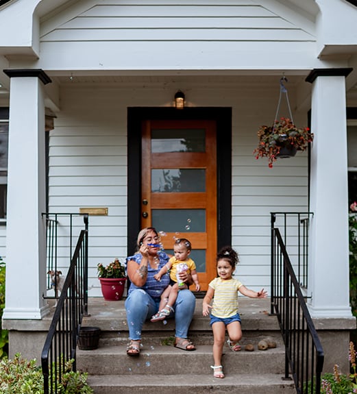 A woman and two children sitting on the steps of a house