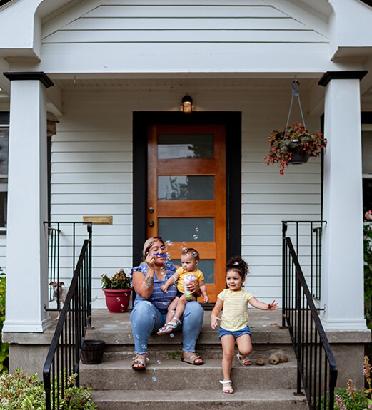 Mother and daughters sitting on the front porch of their home