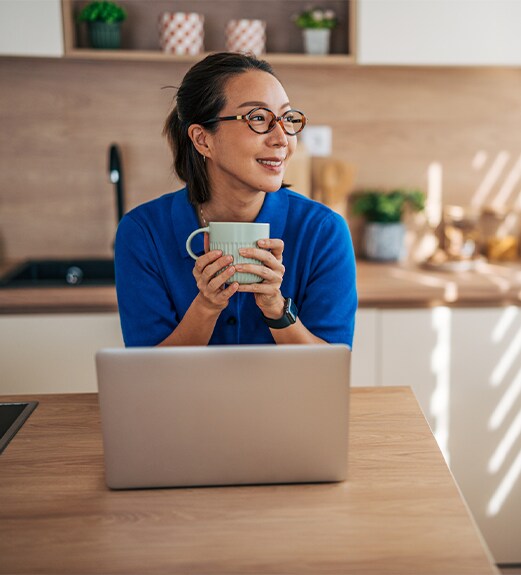 Woman looking out the kitchen window while holding a coffee