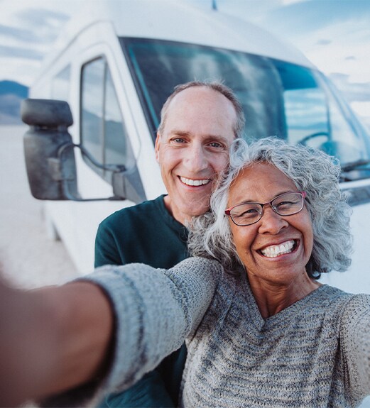 Smiling couple taking a selfie in front of their RV