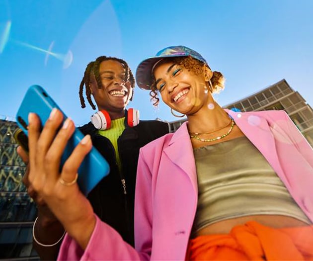 Two friends outside smiling checking out a notification on the phone