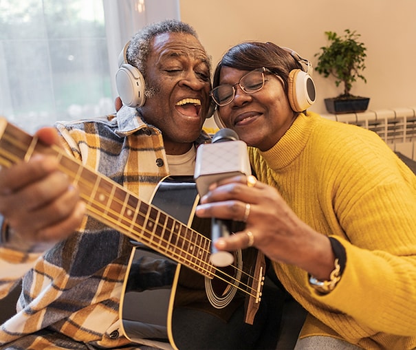 Smiling couple playing music together on a guitar and microphone