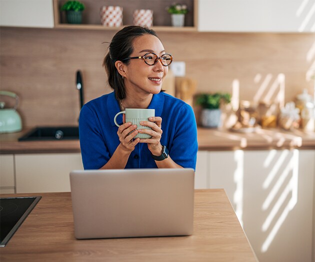 Woman looking out the kitchen window while holding a coffee