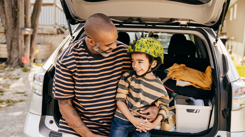 Father sitting with son on the back bumper of the car