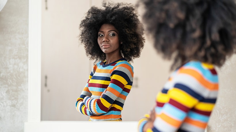 A woman looking confidently at her reflection in a mirror