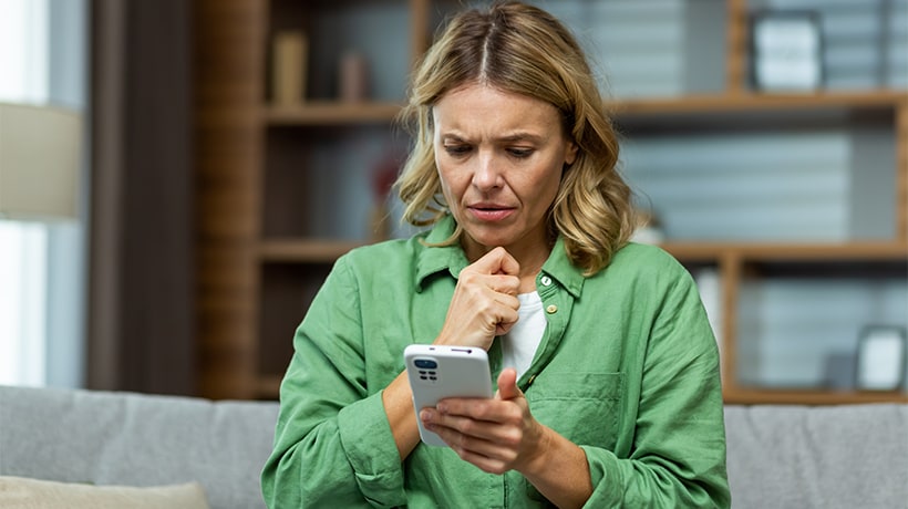 Concerned woman looking at phone worried she is a victim of fraud or a scam.