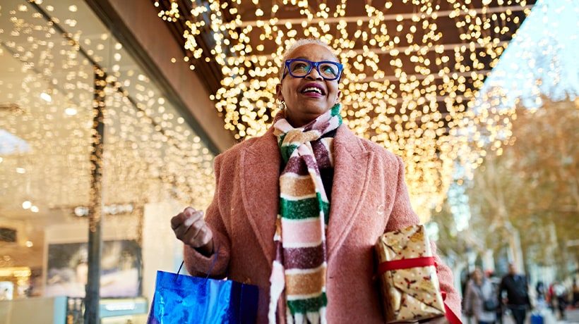 Woman out shopping under holiday lights at a storefront