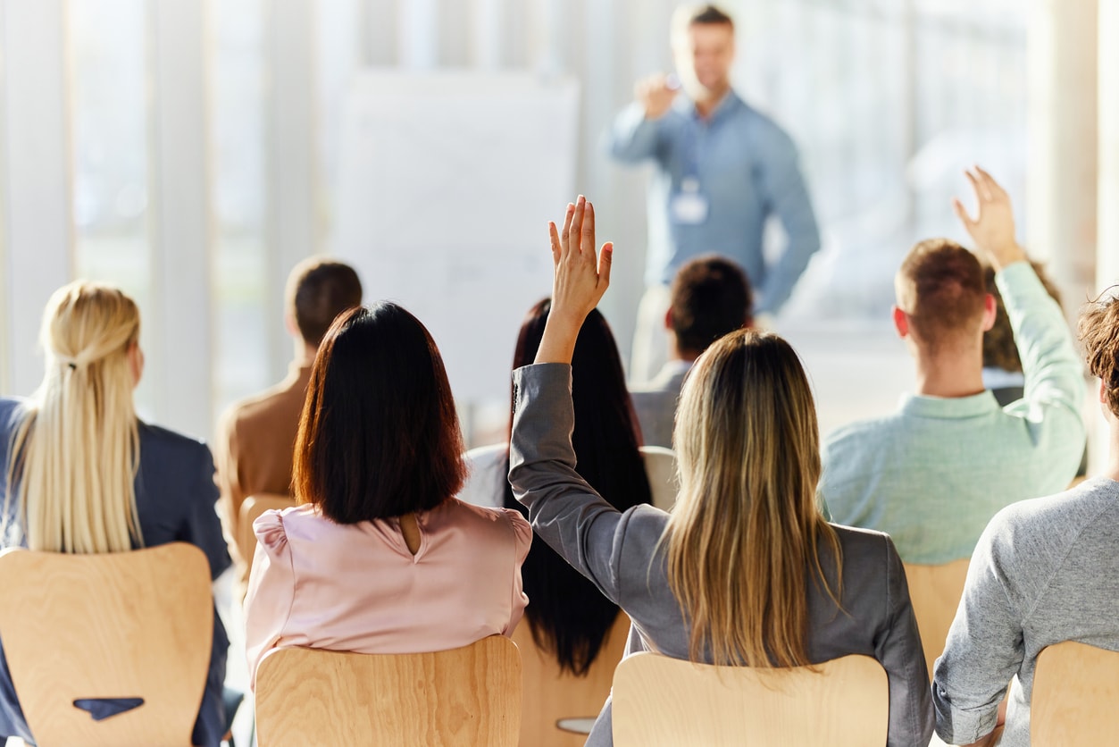 A group of people sitting in chairs raising their hands