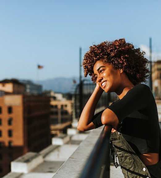 A woman standing on a building rooftop looking out into the distance.