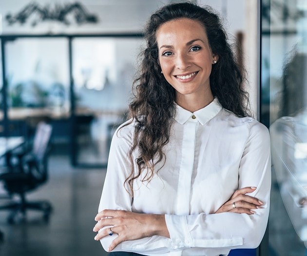 A smiling woman standing with her arms crossed over her torso