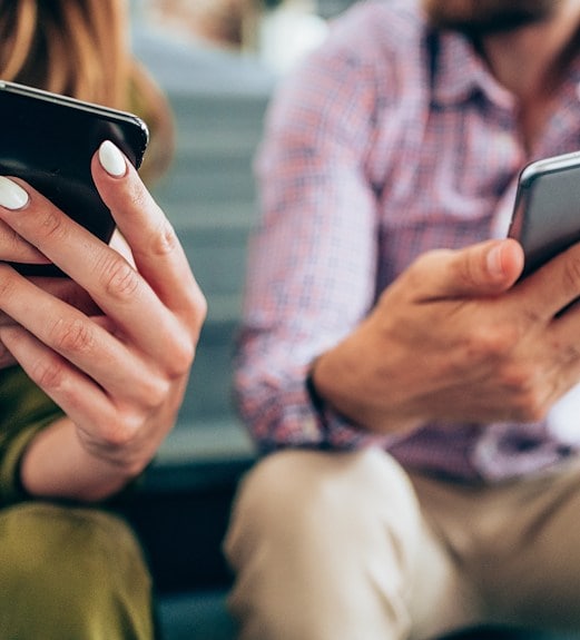 Close up view of two people looking at their phones to access UCU digital banking