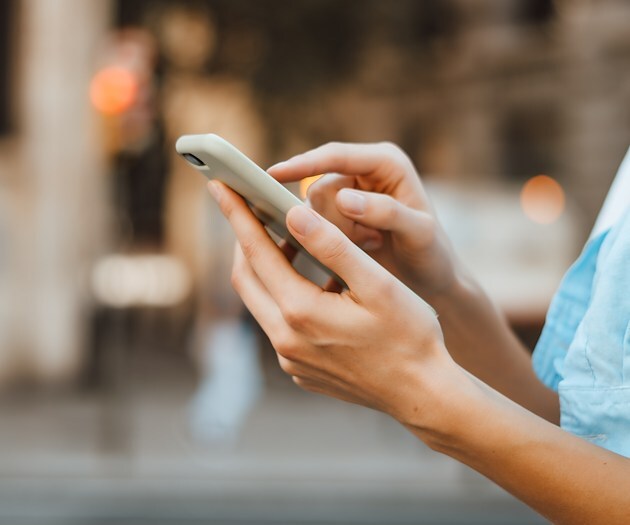 A hand typing on a smart phone.