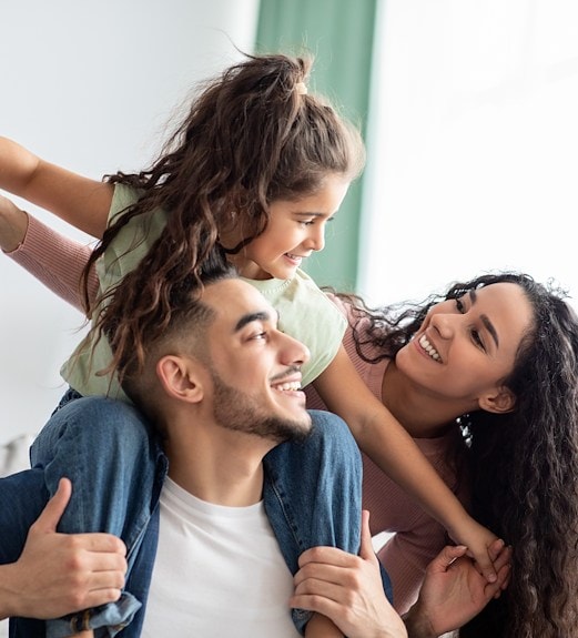 Happy young family with father holding daughter on his shoulders