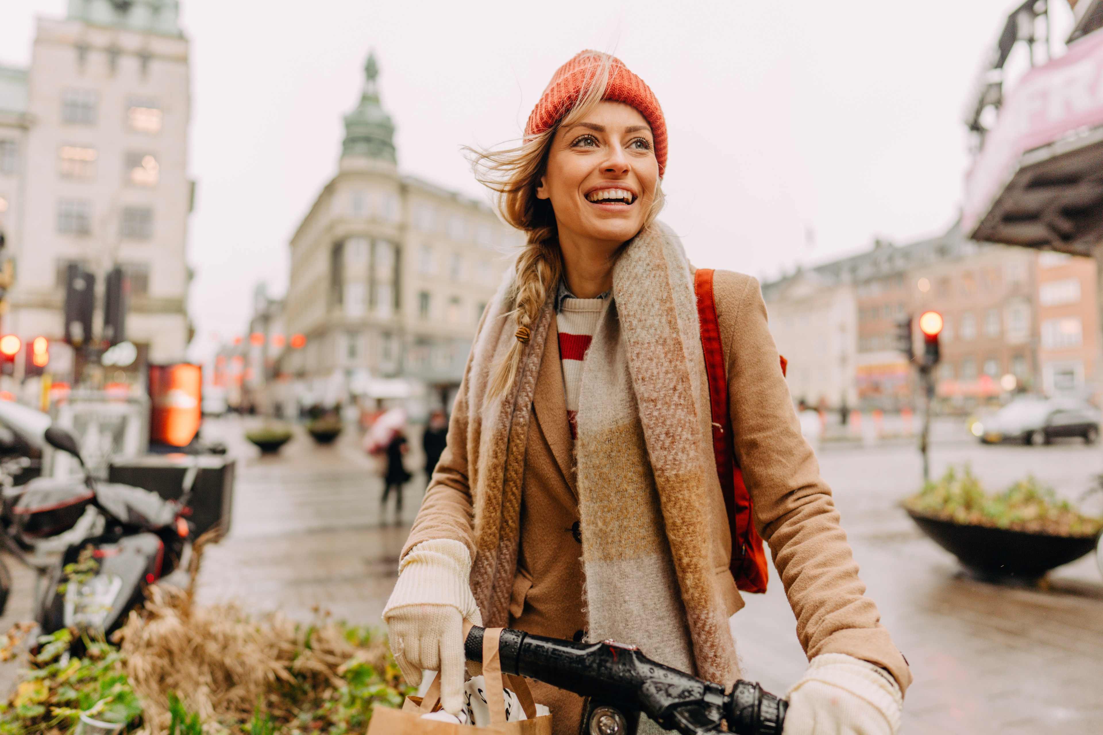 A woman in a red hat and scarf riding a bicycle