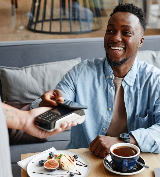 A man a a restaurant using Apple Pay to pay for his meal