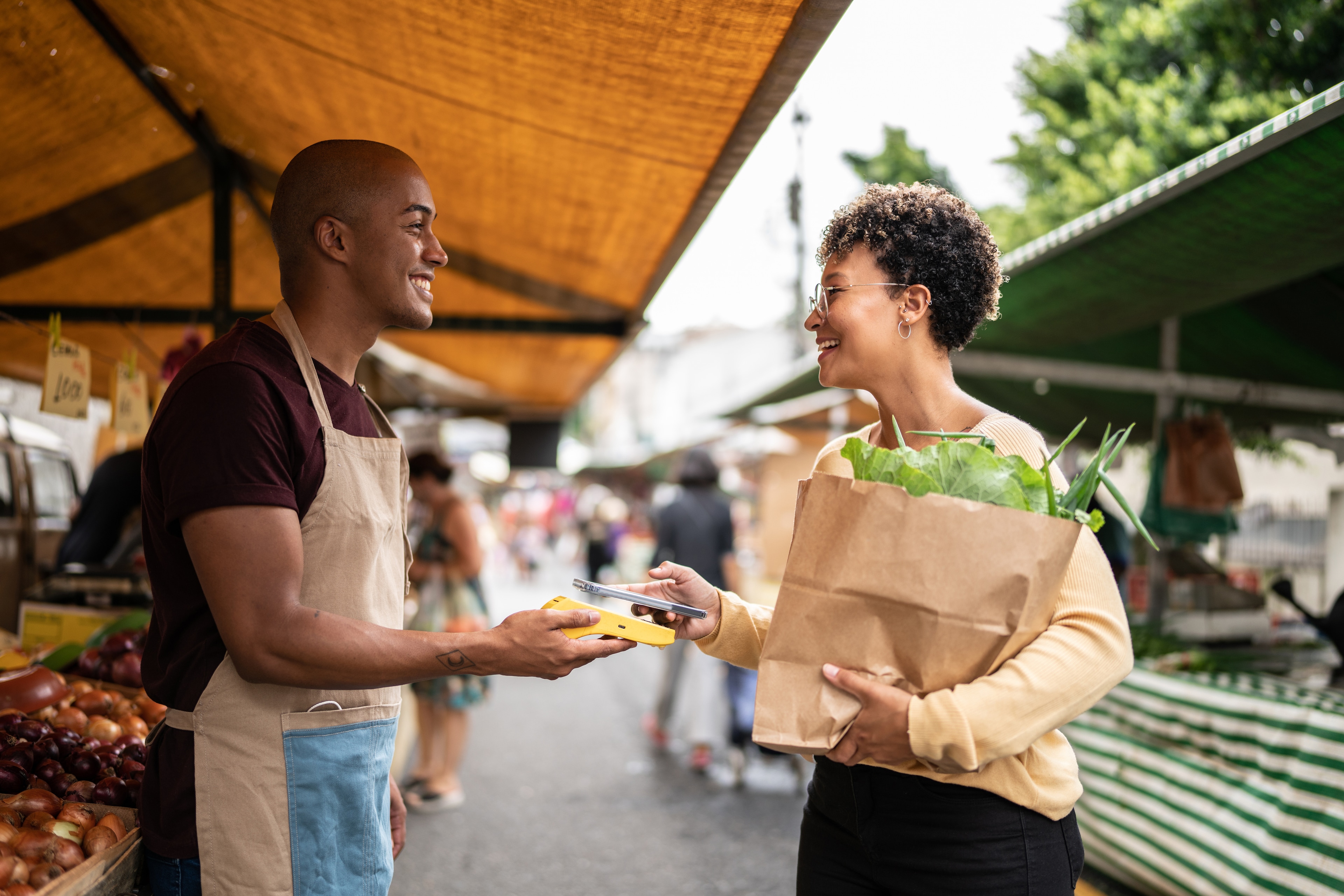 A man and woman holding a bag of vegetables