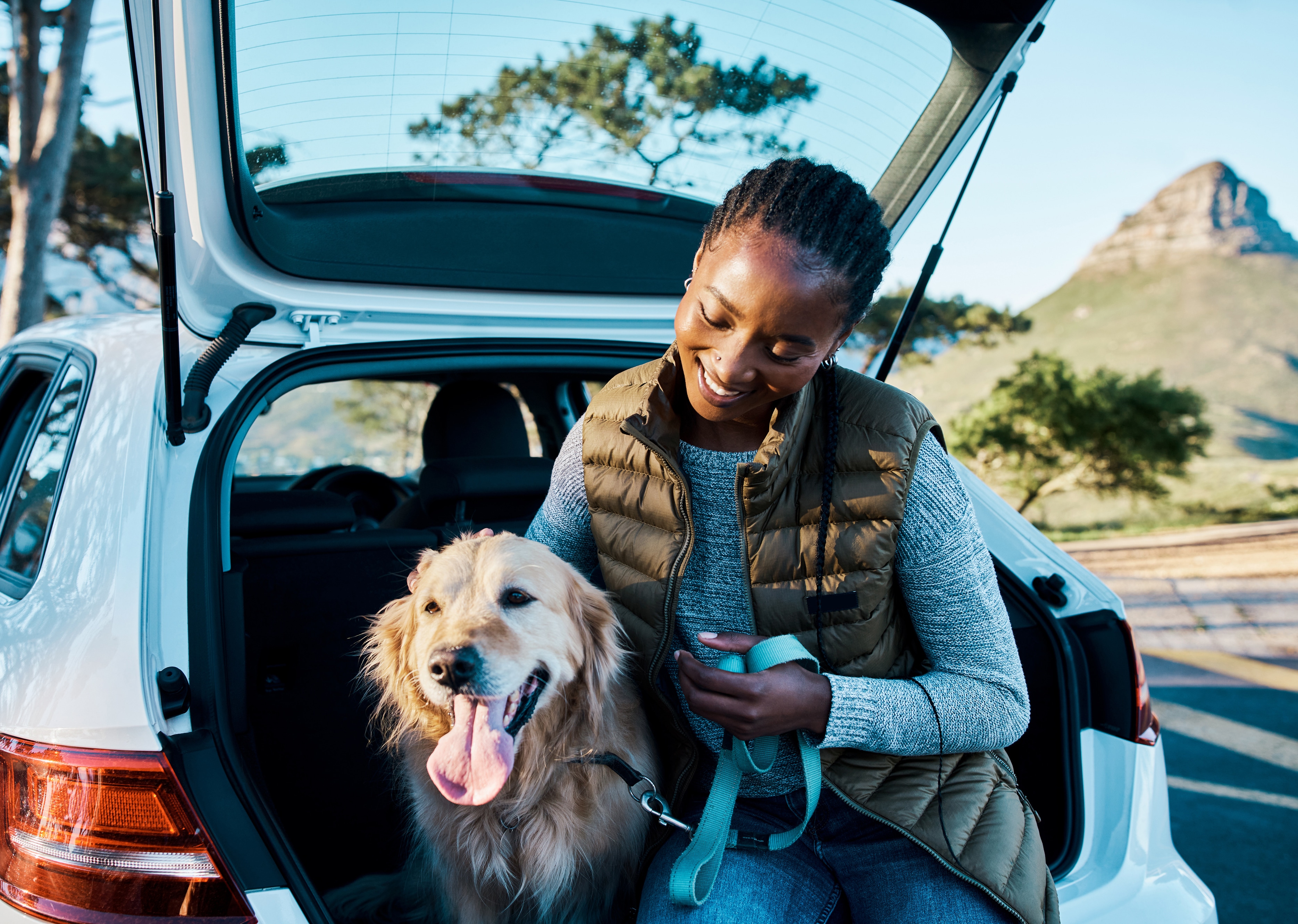 A woman sitting in the back of a car with a dog