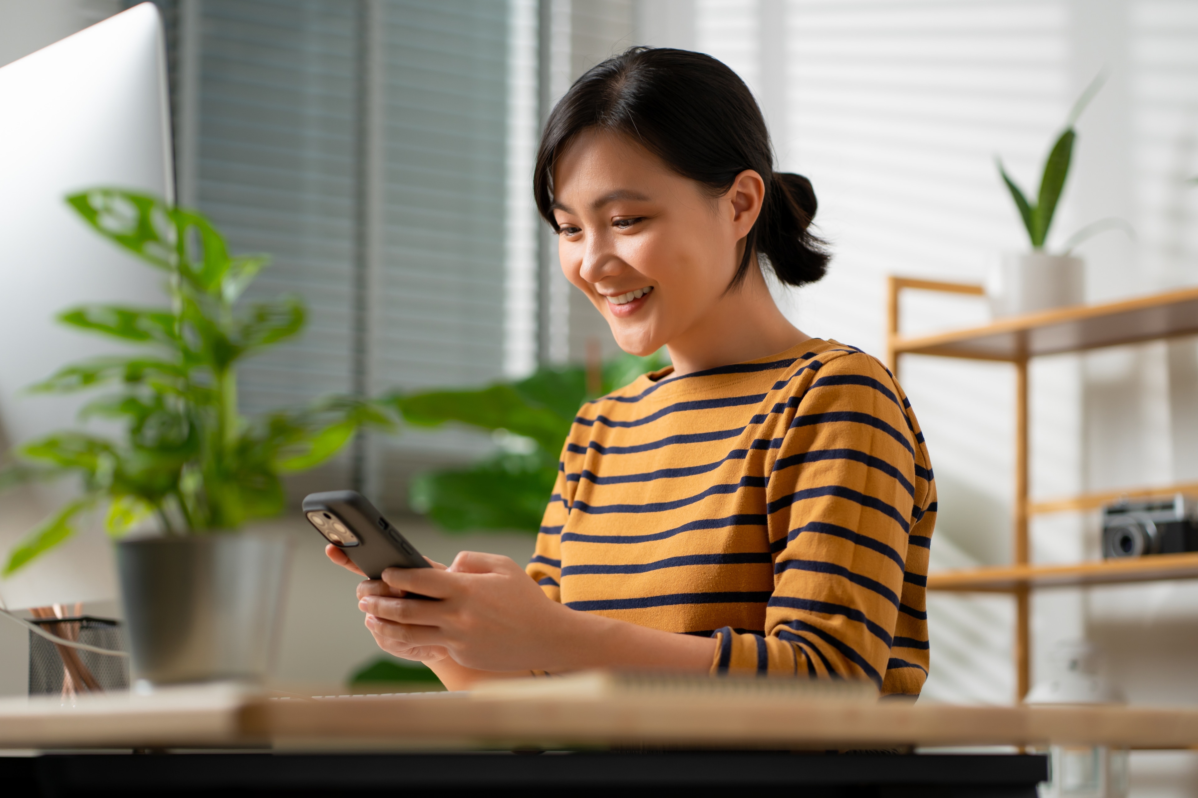 A woman smiling while looking at a phone