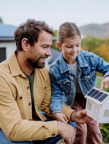 Father holding a model home with his child
