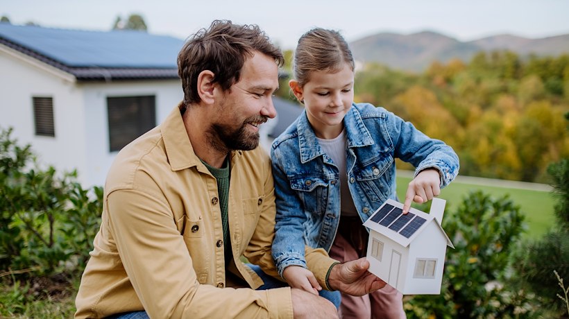 A man and girl looking at a model of a house