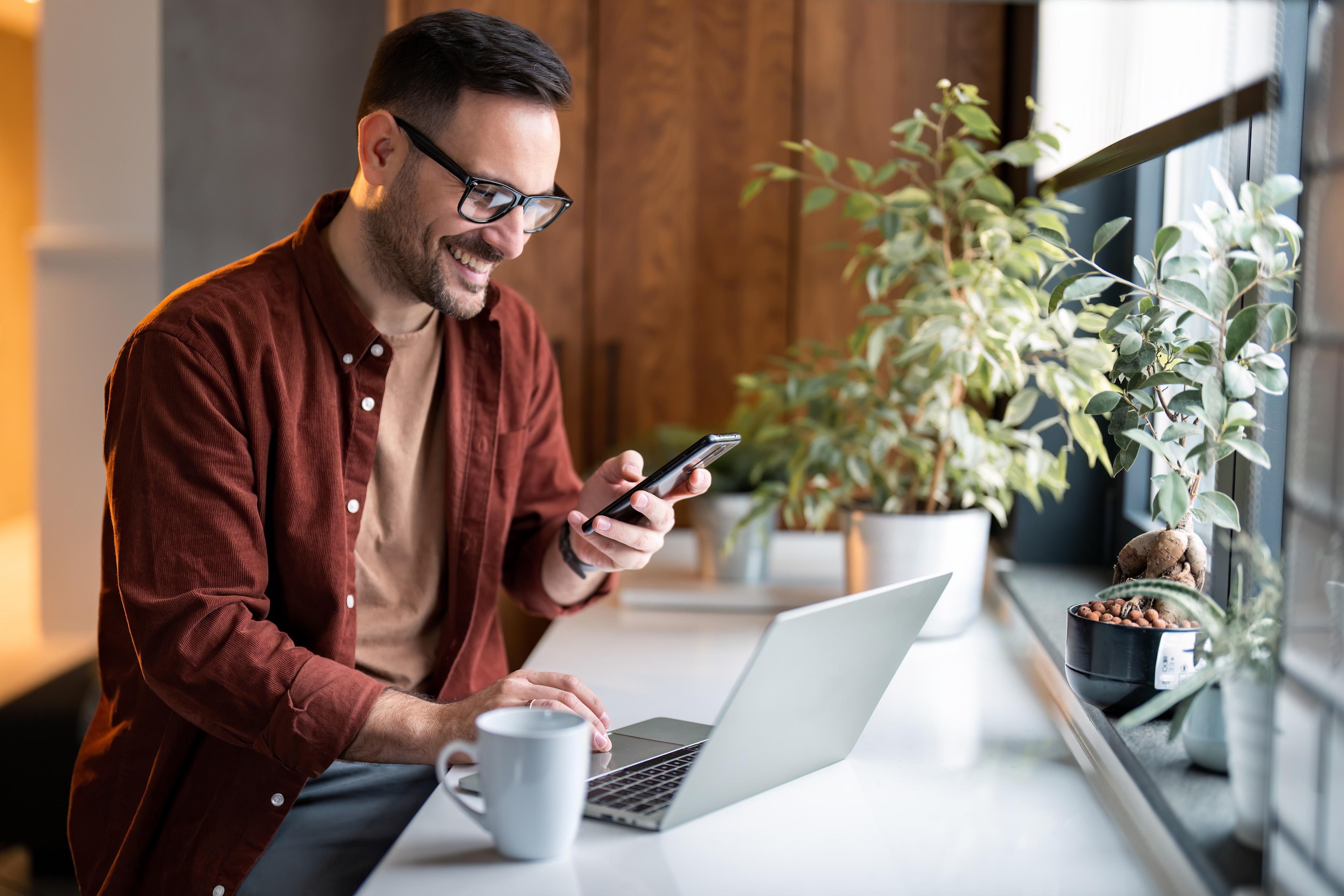 A man sitting at a table with a laptop and a phone
