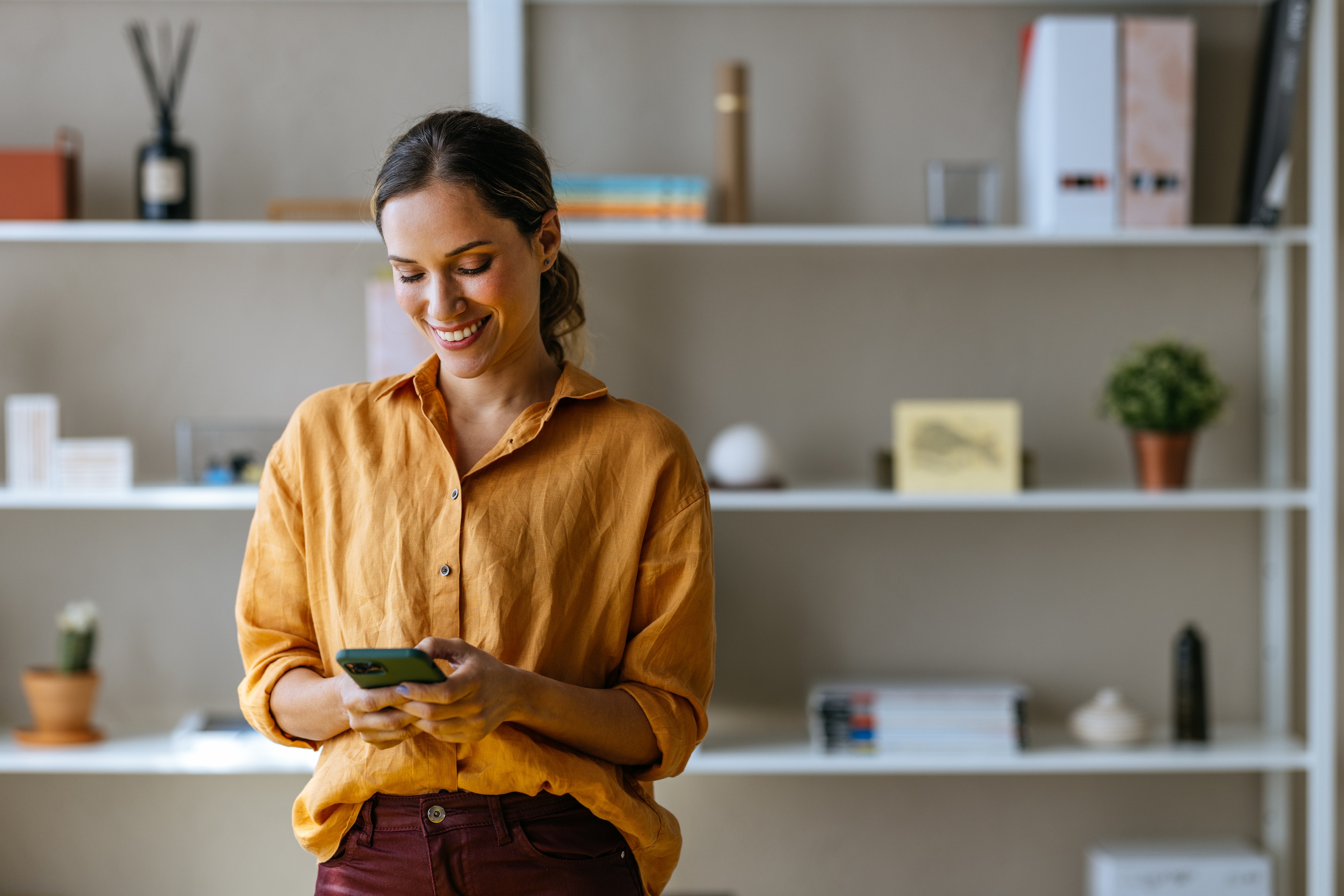 A woman in a yellow shirt looking at a cellphone
