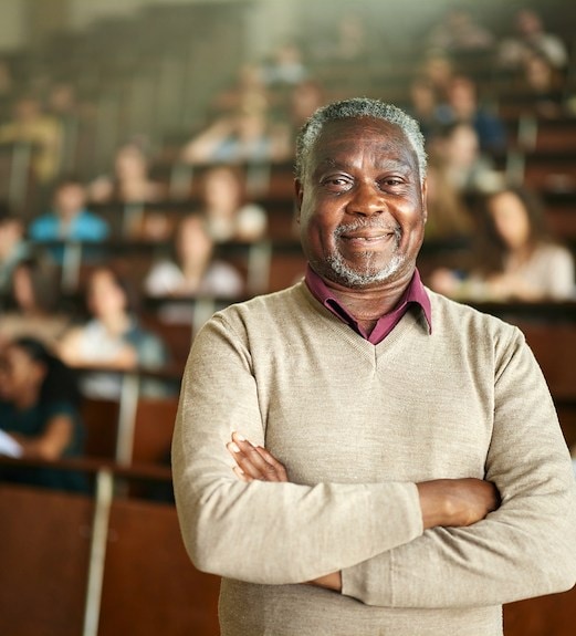 Smiling professor standing with crossed arms in front of his class