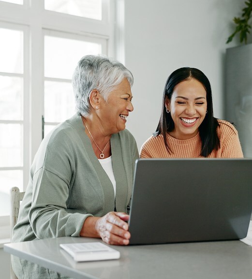 Daughter showing her elderly mother how to make a wire transfer on the computer