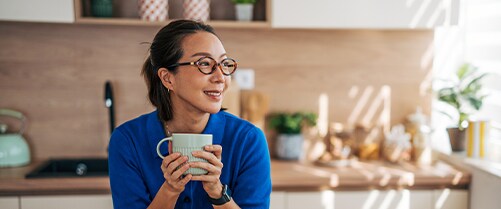 Woman holding a coffee in her kitchen