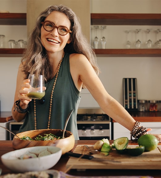 Woman enjoying a green juice smiling in her kitchen