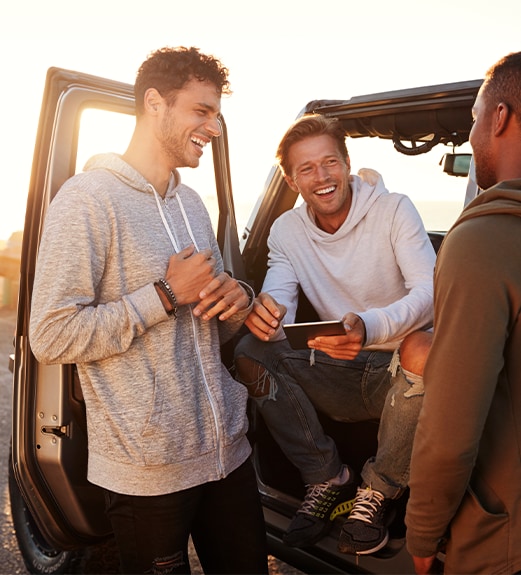 Group of young men hanging out together near a car
