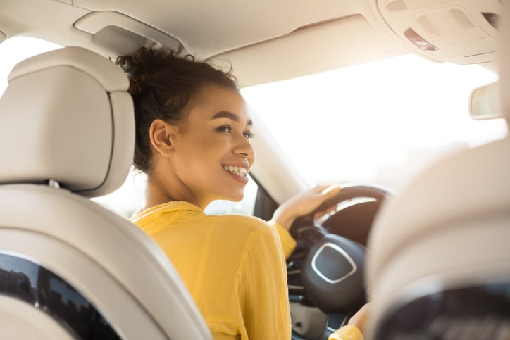 Young woman looking back sitting in the driver's seat of her car