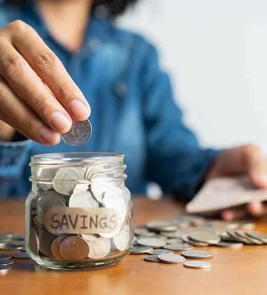 Close up view of adding coins to a savings jar