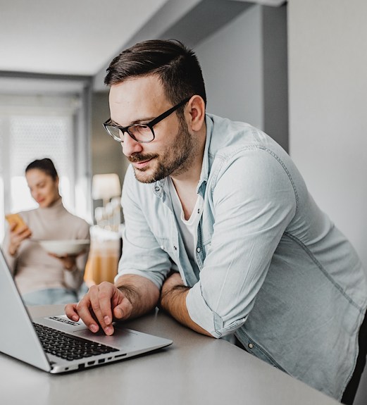 Man leaning over laptop ready to submit an application online