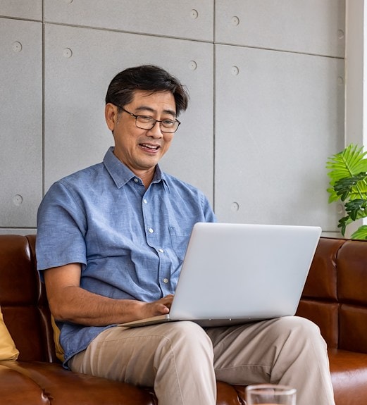 Middle aged man sitting reviewing personal loan options on his laptop
