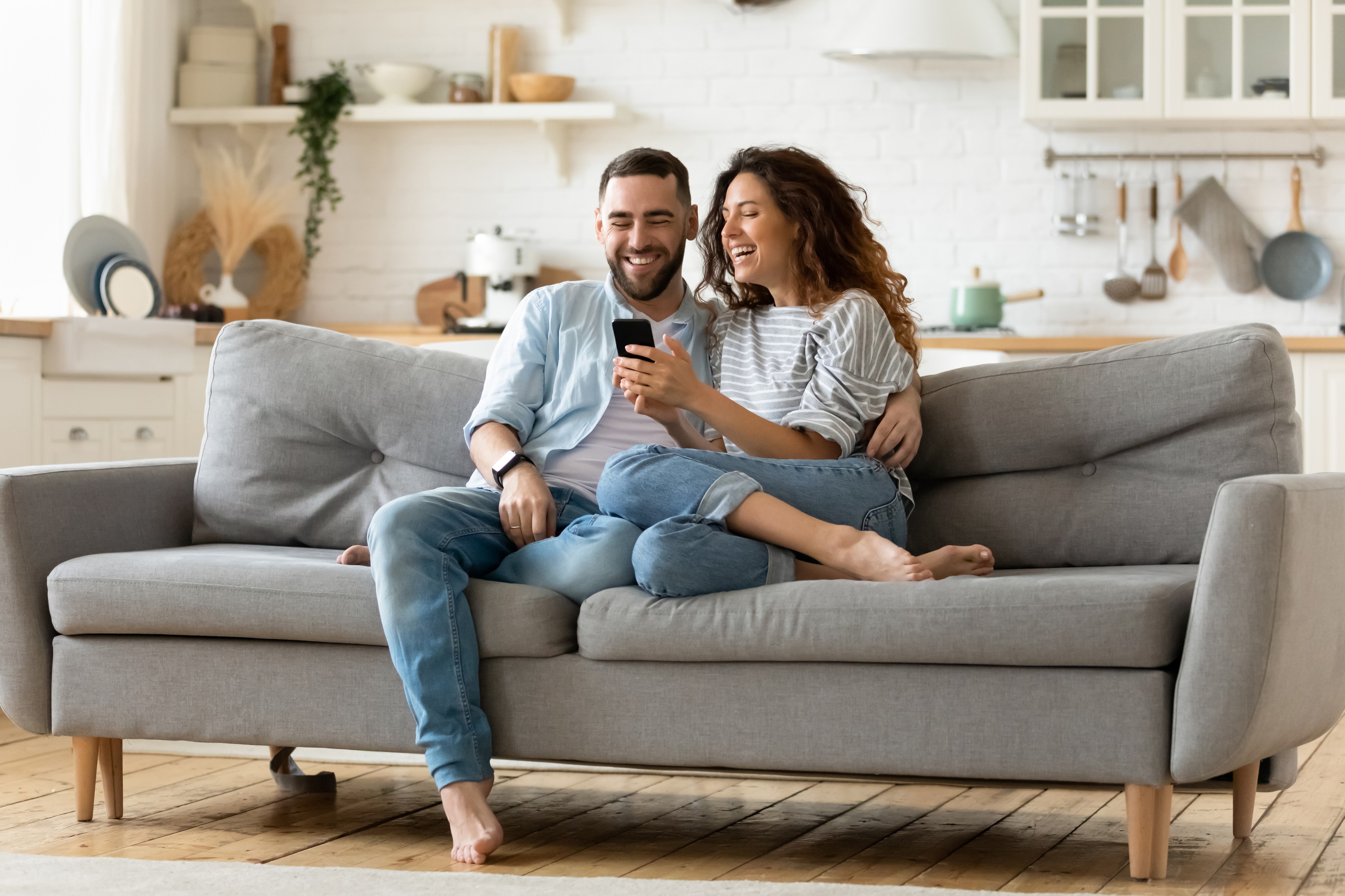 A man and woman sitting on a couch looking at a phone