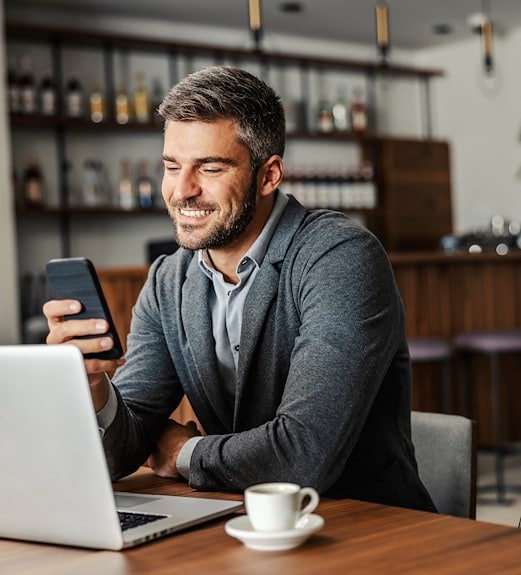 Man checking his banking account on his phone in a coffee shop