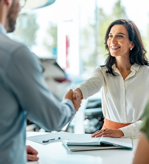 Woman shaking hands with auto dealer