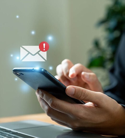 News alert icon floating over a hand holding a phone