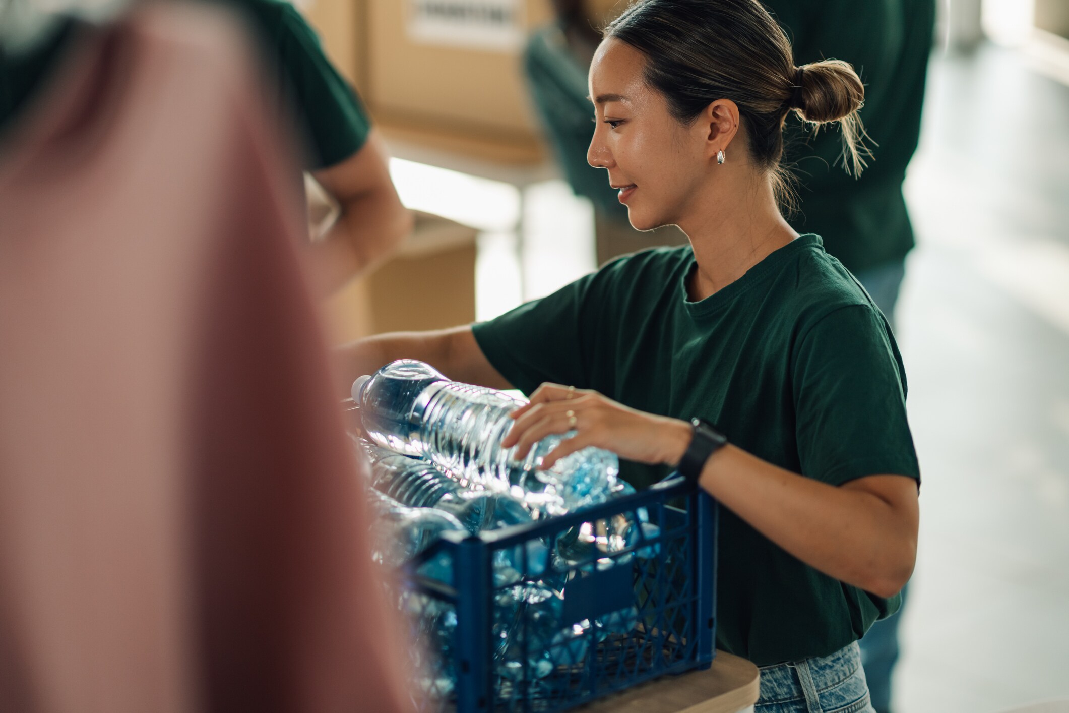 A woman holding a blue crate of water