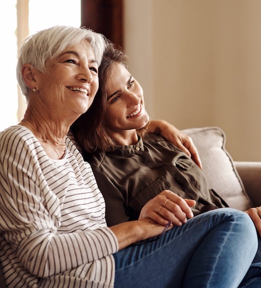 Woman and her mother sitting together on the couch at home