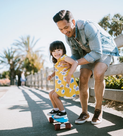 Father showing his young daughter how to skateboard