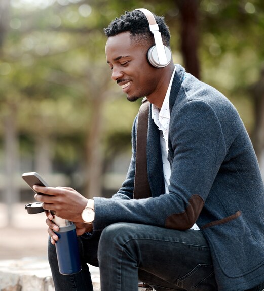 Smiling young man sitting outside watching how-to videos on his phone