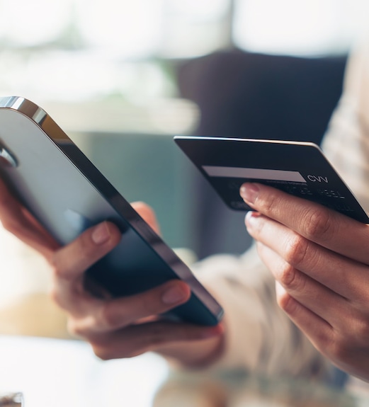 Close up of person's hands holding a credit card and phone