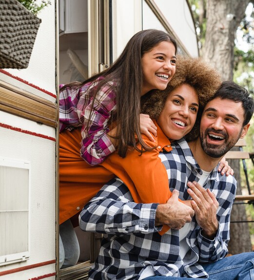 Happy family sitting outside of their RV that they financed via a UCU RV loan