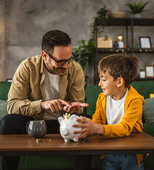 Father showing son how to save money with a piggy bank