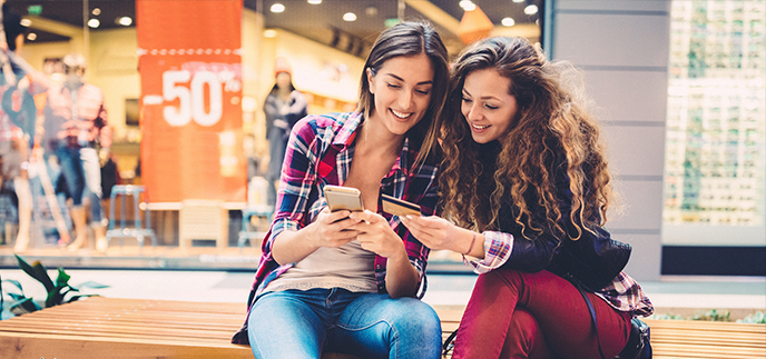 Two friends sitting together outside a shop